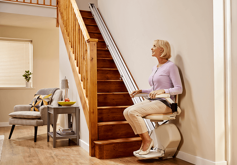 how much does a stairlift cost illustrated by a image of a stairlift with a happy woman going upstairs